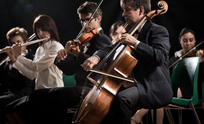 Ausschnitt eines Orchesters. Darauf zu sehen drei Personen, die live spielen.